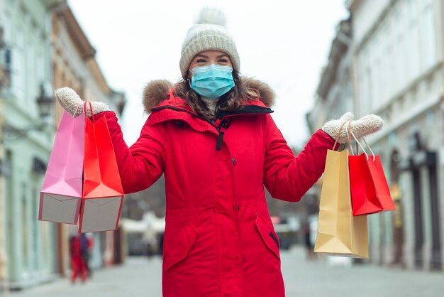 Ritratto di donna adulta con borse della spesa e che indossa una maschera concetto di coronavirus