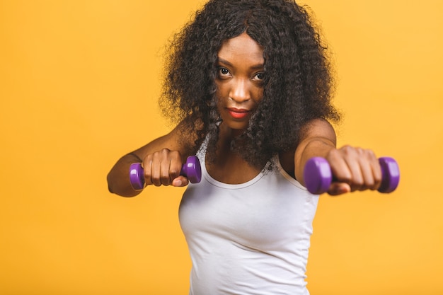 Ritratto di donna afro-americana che esercita il suo muscolo con manubri