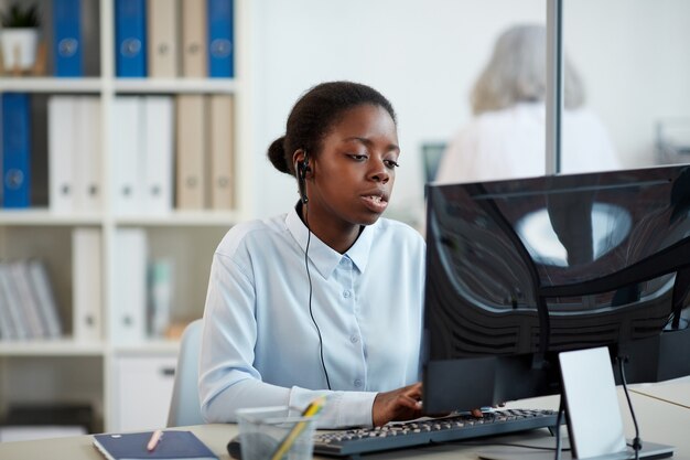 Ritratto di donna afro-americana che indossa l'auricolare mentre si lavora come operatore di call center in ufficio interno