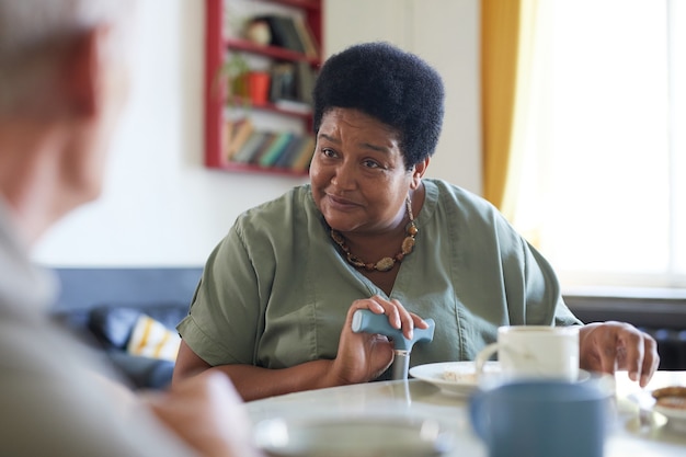Ritratto di donna afroamericana anziana che si gode la colazione nella sala da pranzo della casa di cura