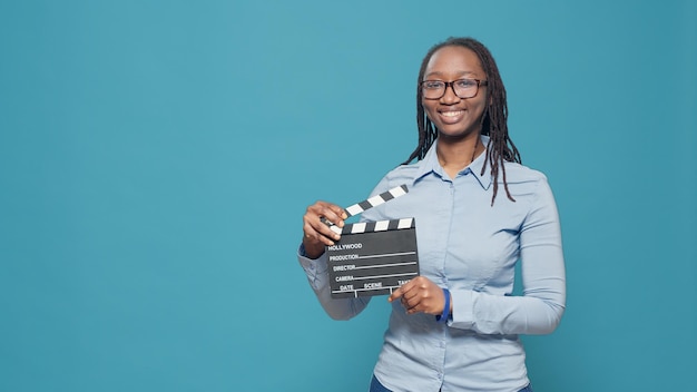 Ritratto di donna afroamericana in possesso di una scheda di ardesia cinematografica utilizzata nell'industria cinematografica e cinematografica. Utilizzo di ciak d'azione come regista o produttore nella produzione di film.