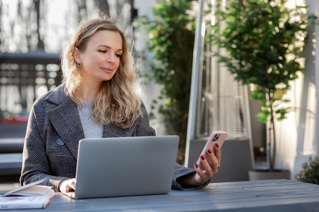 ritratto di donna alla moda che lavora online sul laptop in un moderno caffè all'esterno