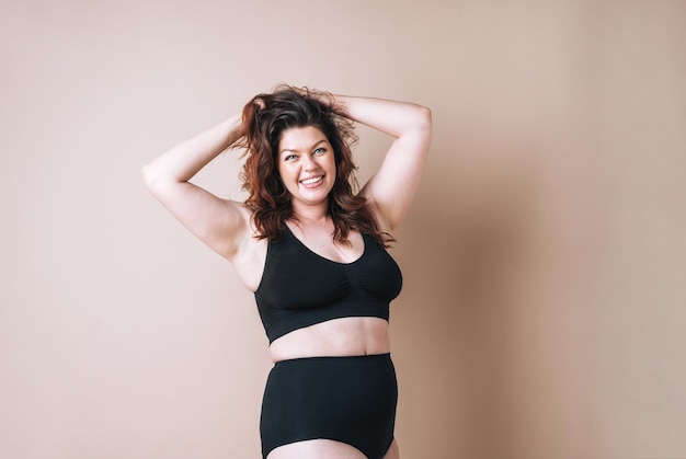 Ritratto di donna amorosa plus size in biancheria intima su sfondo beige amore per il corpo