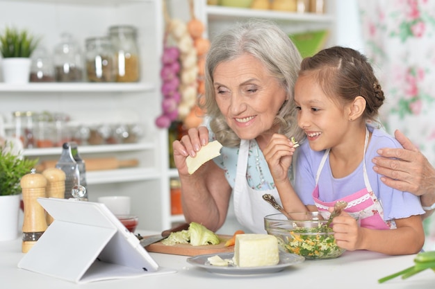 Ritratto di donna anziana con la nipote che prepara la cena