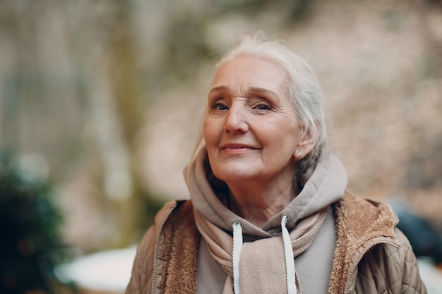 Ritratto di donna anziana dai capelli grigi sorridente all'aperto