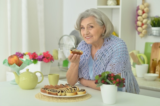 ritratto di donna anziana felice con una gustosa torta a casa