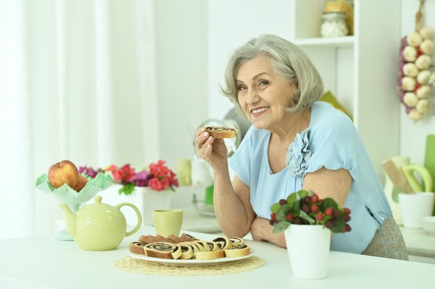 Ritratto di donna anziana felice con una gustosa torta a casa