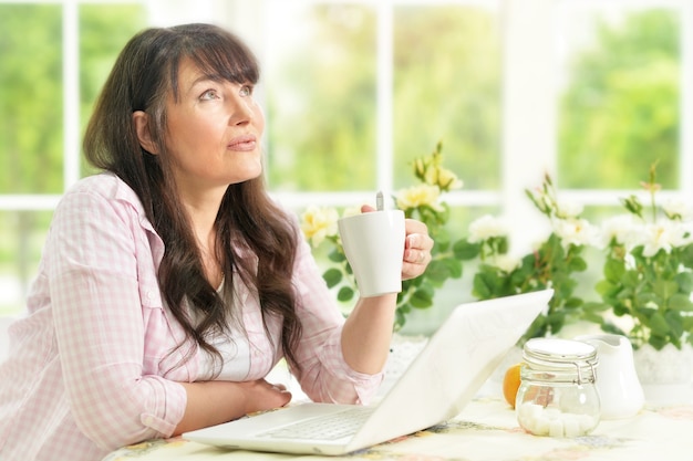 Ritratto di donna anziana ritratto con laptop e caffè