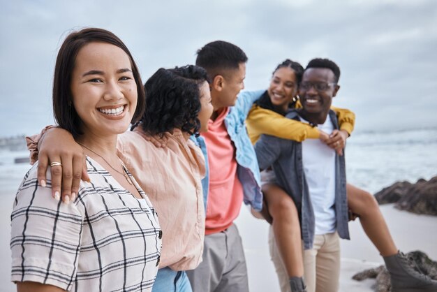 Ritratto di donna asiatica e sorriso di amici in spiaggia oceano e natura all'aperto per divertimento felicità e viaggi Diversità di giovani felici in mare per vacanze e weekend rilassanti insieme