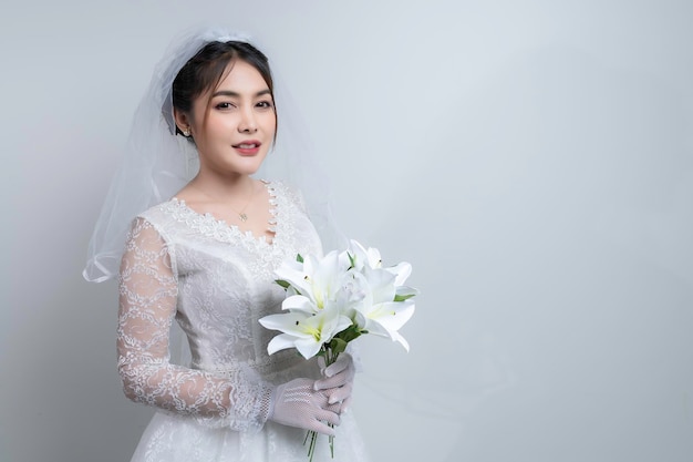 Ritratto di donna asiatica indossare sposa con fiore su sfondo biancoConcetto di matrimonio