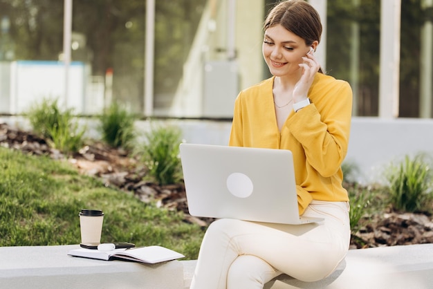 Ritratto di donna attraente che utilizza laptop nello spazio di coworking giovane donna che indossa gli auricolari seduto i