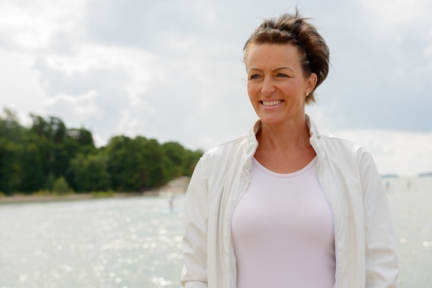 Ritratto di donna bella matura contro la vista panoramica del lago e del cielo in natura