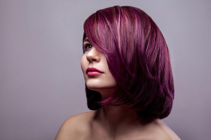 Ritratto di donna bellissima modella con acconciatura e trucco di colore viola corto e distogliendo lo sguardo. girato in studio al coperto, isolato su sfondo grigio.