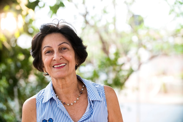 ritratto di donna brasiliana senior guardando la fotocamera nel tramonto e sorridente. Forma orizzontale, copia dello spazio