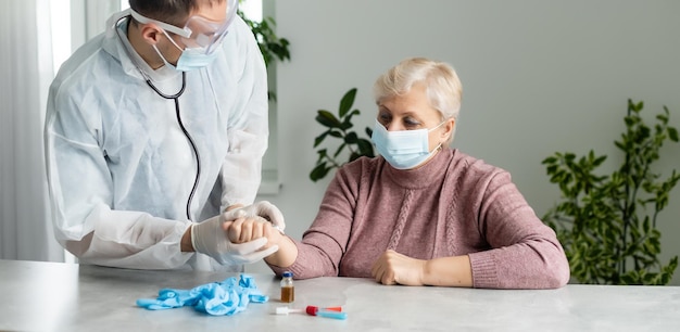 Ritratto di donna caucasica anziana che indossa una maschera medica protettiva. Assistenza agli anziani durante l'epidemia del virus corona, una mano d'aiuto, concetto di assistenza domiciliare.