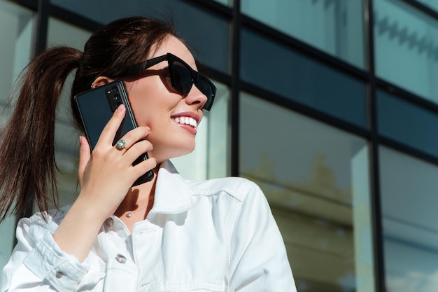 Ritratto di donna caucasica sorridente con denti bianchi che parla al telefono