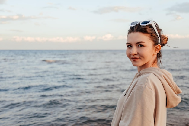 Ritratto di donna caucasica sulla spiaggia che guarda l'obbiettivo al tramonto