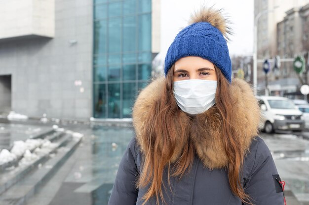 Ritratto di donna che cammina per strada in inverno in una maschera protettiva per proteggere dalle malattie infettive Protezione contro il raffreddore influenza inquinamento atmosferico Concetto di salute