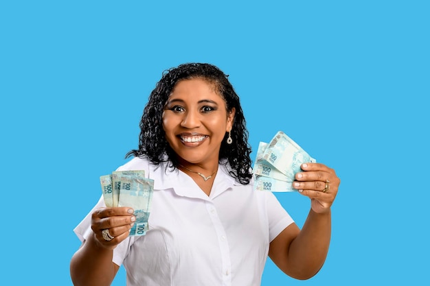 Ritratto di donna che tiene banconote da 100 reais brasiliane in mani afro brasiliane fiduciose
