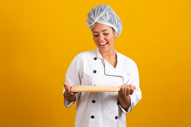 Ritratto di donna chef sorridente con tagliere isolato su sfondo giallo