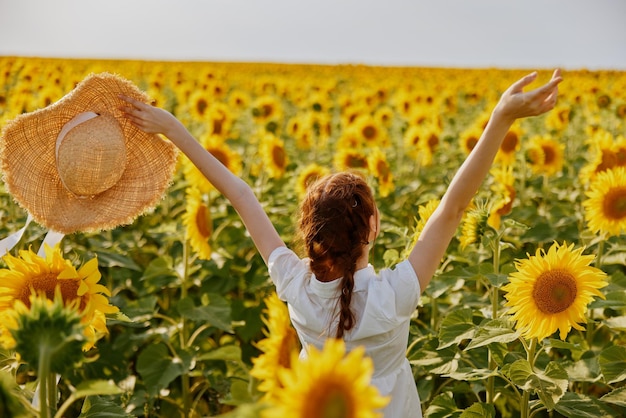 Ritratto di donna con cappello di paglia in abito bianco un campo di girasoli agricoltura inalterata