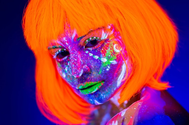 Ritratto di donna con trucco al neon. Vernice fluorescente alla luce ultravioletta