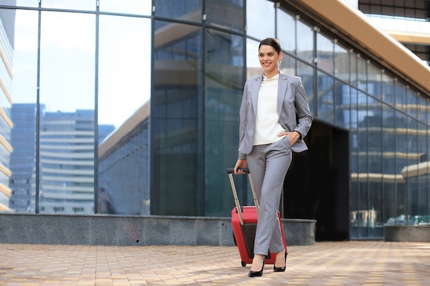 Ritratto di donna d'affari di successo che viaggia con custodia in aeroporto. Bellissimo viaggio femminile alla moda con i bagagli.