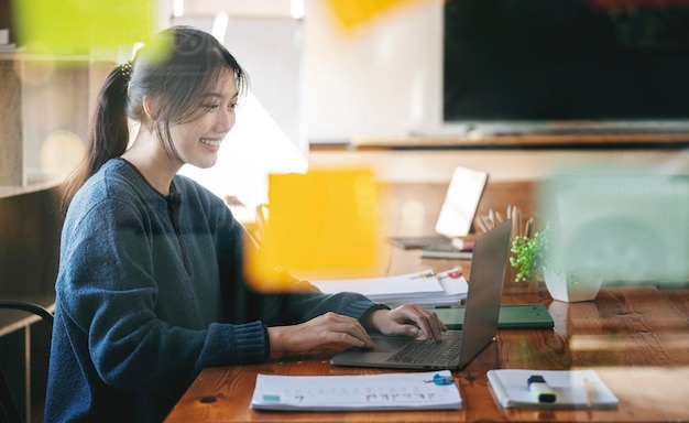 Ritratto di donna d'affari felice seduto sul posto di lavoro in ufficio Giovane lavoratrice attraente utilizzando il computer portatile moderno