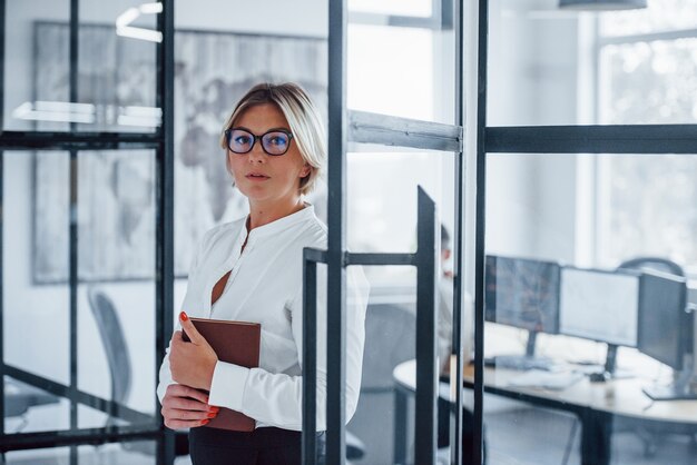 Ritratto di donna d'affari in abiti formali che sta in ufficio.