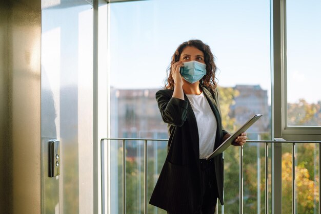 Ritratto di donna d'affari in maschera protettiva Il responsabile dell'ufficio torna al lavoro in ufficio