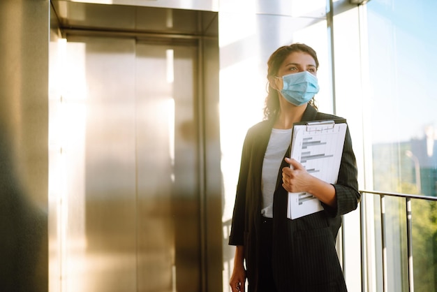 Ritratto di donna d'affari in maschera protettiva Il responsabile dell'ufficio torna al lavoro in ufficio