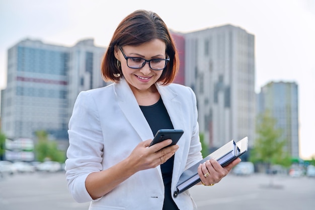 Ritratto di donna d'affari matura di successo con smartphone all'aperto