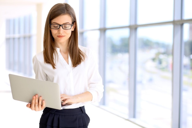 Ritratto di donna d'affari moderna che lavora con il computer portatile nell'area dello spazio della copia dell'ufficio