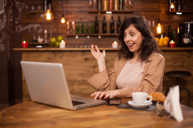 Ritratto di donna d'affari sorpresa durante una videochiamata in una moderna caffetteria. Giovane imprenditore tramite computer portatile. Donna d'affari che lavora nel suo tempo libero. Ritratto di donna d'affari di successo.