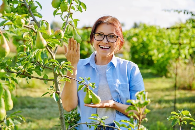 Ritratto di donna di mezza età sicura sorridente nel frutteto vicino al pero