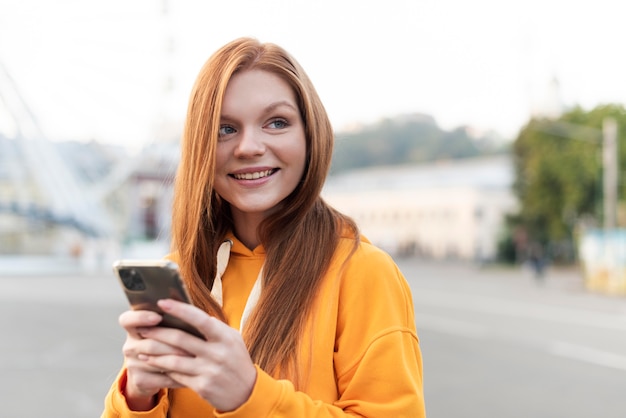 Ritratto di donna di redhead controllando il suo telefono con copia spazio