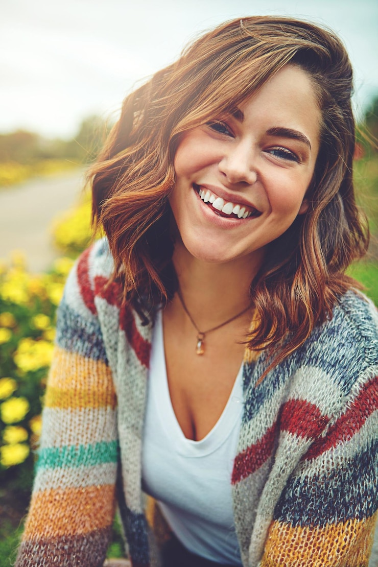 Foto ritratto di donna e fiori con sorriso sul campo o in autunno ambiente di campagna o all'aperto faccia di persona femminile e margherite floreali al sole con felicità per l'inghilterra viaggio prato o vacanza