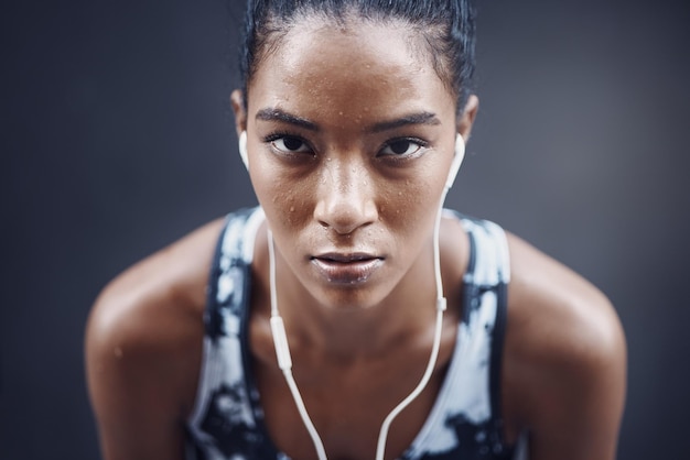 Ritratto di donna e pausa musicale in corsa all'aperto e stanchezza dell'atleta con sudore sullo sfondo grigio Persona femminile esausta e cuffie per ascoltare canzoni stanche e sfida cardio con audio