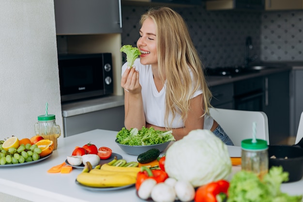 Ritratto di donna felice al tavolo a mangiare un alimento sano.