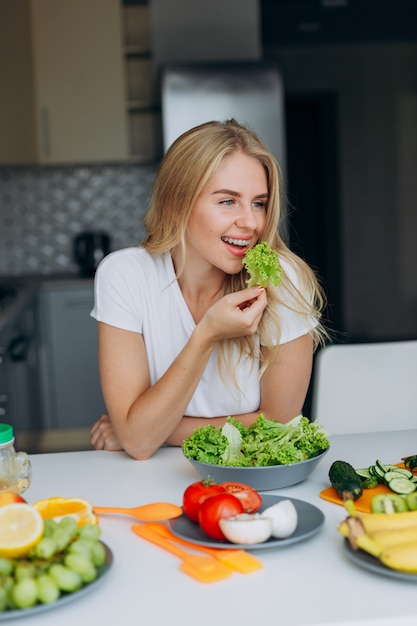 Ritratto di donna felice al tavolo a mangiare un alimento sano.