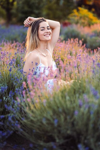 Ritratto di donna felice con sorriso tra cespugli di lavanda Ragazza con catena d'oro tra lavanda