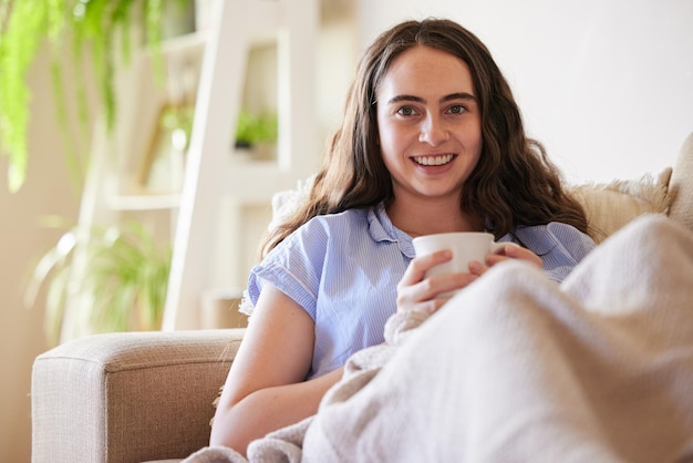 Ritratto di donna felice e bere caffè sul divano del divano e rilassarsi nel soggiorno e nell'appartamento in Svezia Giovane ragazza a casa godersi una tazza di tè pace e libertà al mattino con una bevanda calda