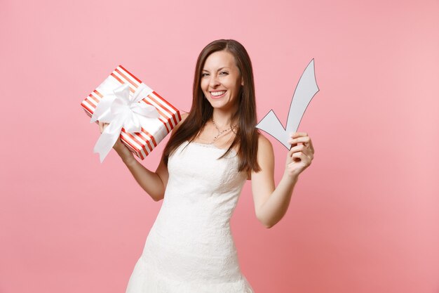 Ritratto di donna gioiosa in abito bianco con casella rossa con segno di spunta con regalo, regalo