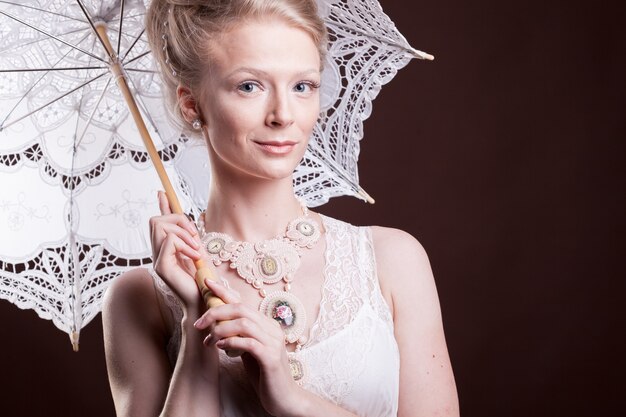 Ritratto di donna in abito vintage che tiene un ombrello di pizzo. Ricco e vintage. Lusso ed eleganza. Foto in studio