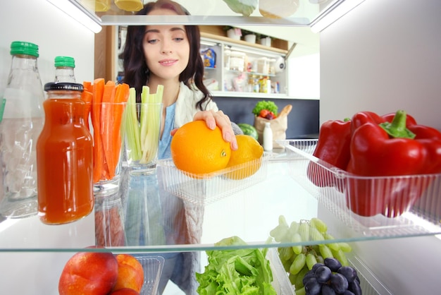 Ritratto di donna in piedi vicino al frigorifero aperto pieno di frutta e verdura di cibo sano Ritratto di donna