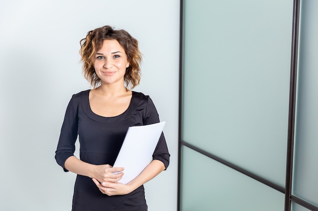 Ritratto di donna in ufficio bianco con documenti isolati.