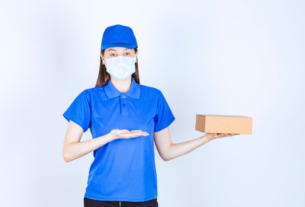 Ritratto di donna in uniforme e maschera medica che tiene in mano una scatola di carta
