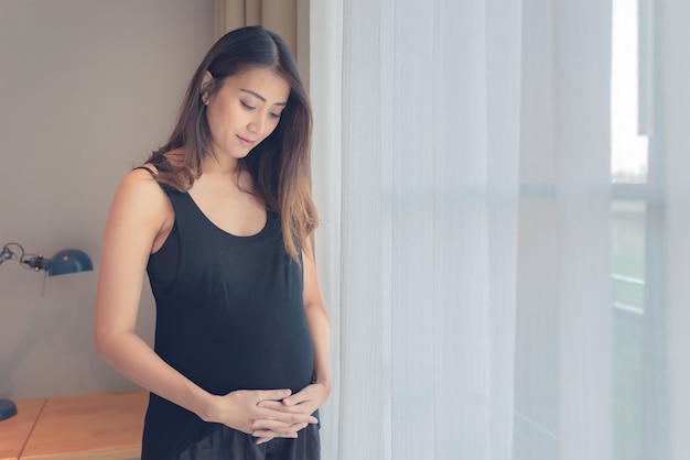 Ritratto di donna incinta asiatica in camera da letto