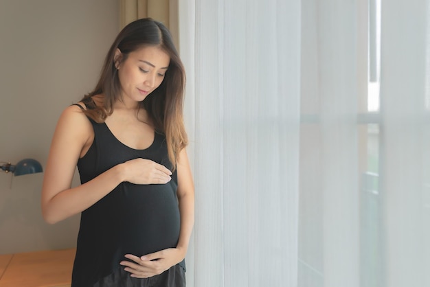 Ritratto di donna incinta asiatica in camera da letto