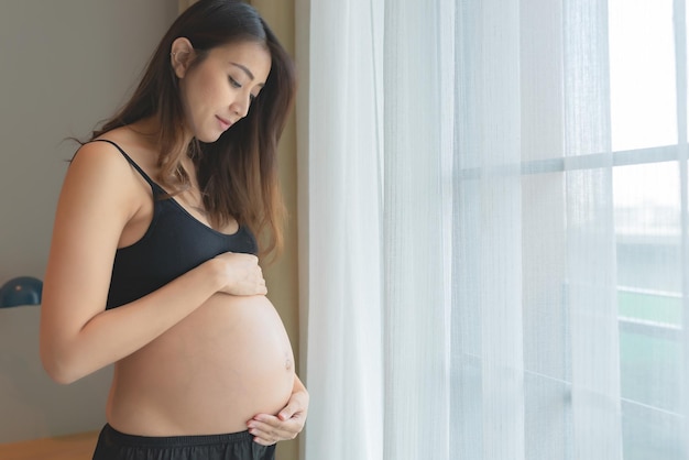 Ritratto di donna incinta asiatica in camera da lettoFelice concetto di festa della mamma